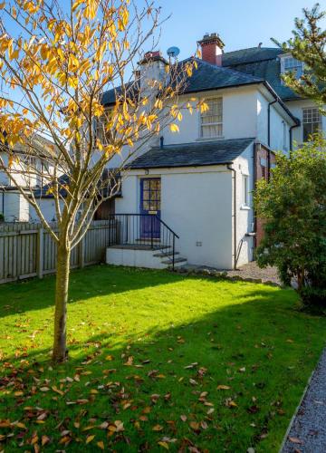 a white house with a tree in the yard at The Garden Apartment in Keswick