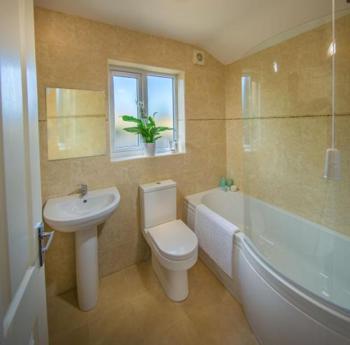 a bathroom with a toilet and a sink and a bath tub at The Garden Apartment in Keswick