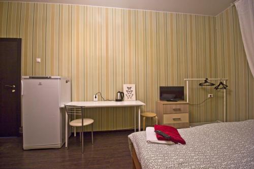 モスクワにあるLakshmi Rooms Park Pobedyのベッド、デスク、冷蔵庫が備わる客室です。