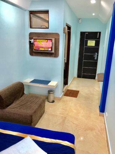 a living room with a couch and a tv on the wall at Hotel Landmark in Ooty