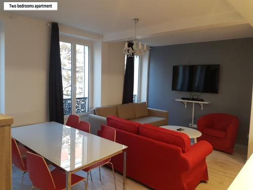 ヴァンセンヌにあるMeublés de Tourisme à Vincennesのリビングルーム(赤いソファ、テーブル付)