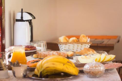 a table topped with different types of bread and fruit at Villa Cottage Pousada in Monte Alegre do Sul