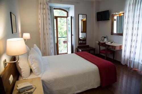 a bedroom with a bed and a desk with a telephone at Hotel Solaris in Setúbal