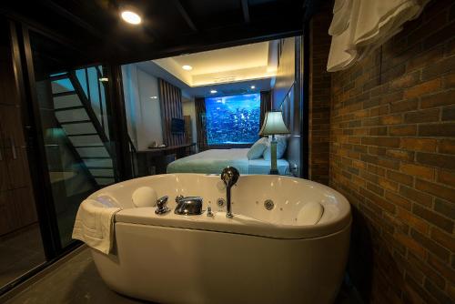 V20 Boutique Jacuzzi Hotel - SHA Extra Plus في بانكوك: حوض استحمام في غرفة مع غرفة نوم