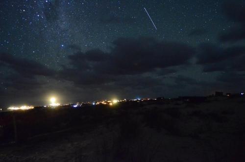 a starry night with a plane flying in the sky at cabopolonioalojamiento in Cabo Polonio