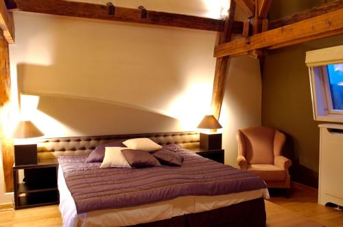 a bedroom with a large bed and a chair at Chateau-Hotel De Belmesnil in Saint-Denis-le-Thiboult
