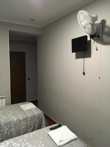 a room with two beds and a tv on the wall at Pensión La Bilbaina - Albergue Logroño in Logroño