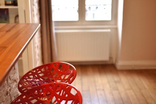 a red chair sitting next to a counter with a window at L'Appart Elegance Part Dieu in Lyon