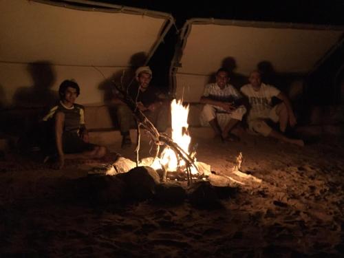 a group of people sitting around a fire at RUM STARDUST lUXURY CAMP in Wadi Rum