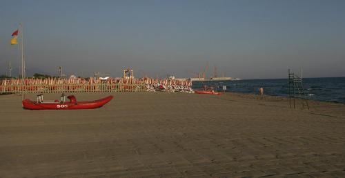 a beach with a red boat on the beach at Hotel Tenda Rossa in Marina di Carrara