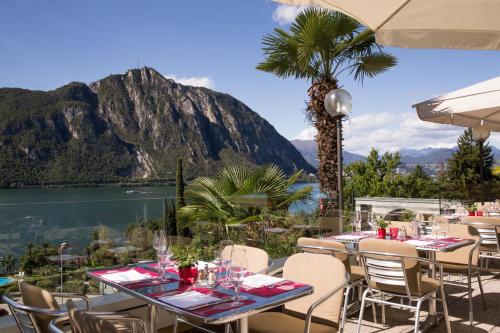 a restaurant with a view of the water and mountains at Hotel Campione in Bissone