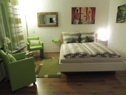 a bedroom with a bed and two green chairs at Grün und herzlich in Oberstaufen