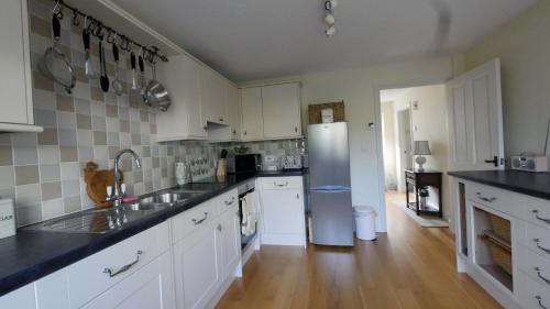 a kitchen with white cabinets and a stainless steel refrigerator at Frome Cottages in Evershot