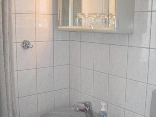 Baño de azulejos blancos con lavabo y espejo en Haus Peters, en Büsum