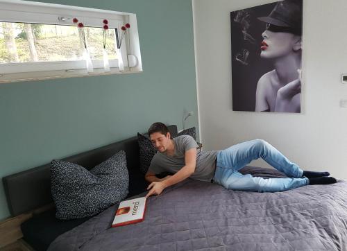 a man laying on a bed with a book at Ferienhaus im Erzgebirge in Chemnitz