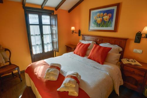 a bedroom with a large bed with orange walls at Cai Llope in Oviñana