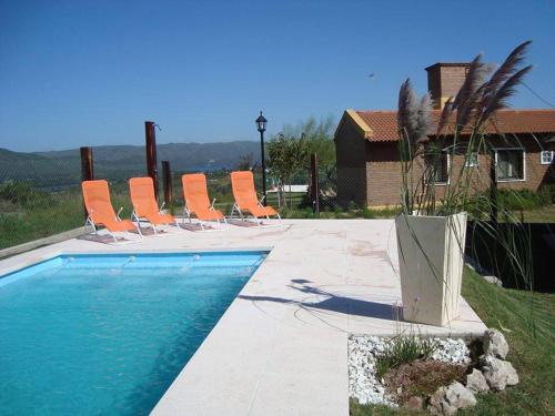 Un grupo de sillas junto a una piscina. en Cabañas Villa del Mirador, en Bialet Massé
