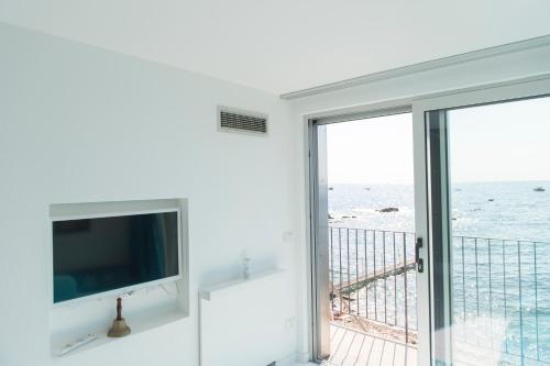 a living room with a tv and a balcony with the ocean at L'Oblò in Massa Lubrense