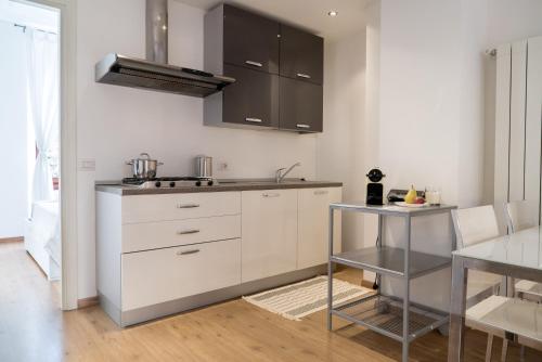 ミラノにあるCharming Sempione Apartmentの白いキャビネットとテーブル付きのキッチン