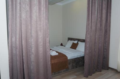 a bedroom with a bed with curtains in a room at Hotel Nabadi in Tbilisi City