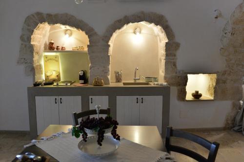 una cocina con dos arcos y una mesa con un jarrón. en Trullo Assenzio, en Alberobello