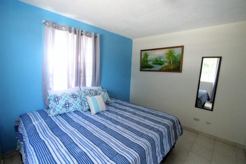 Schlafzimmer mit blauen Wänden und einem Bett mit Fenster in der Unterkunft Turtle Ridge Apartments in Saint James
