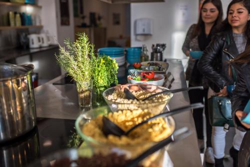 zwei Frauen stehen in einer Küche mit Tisch und Essen in der Unterkunft Avenue Hostel in Budapest