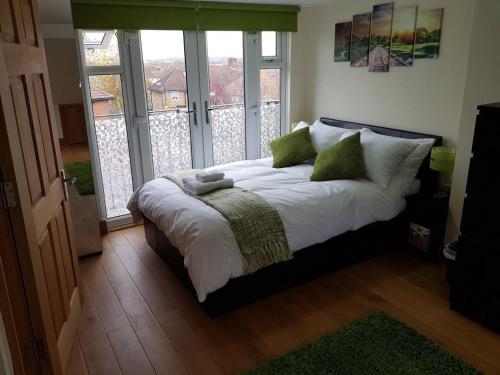 a bedroom with a bed with white sheets and green pillows at Modern ★★★★★ Top Floor Studio Apartment Getaway in London