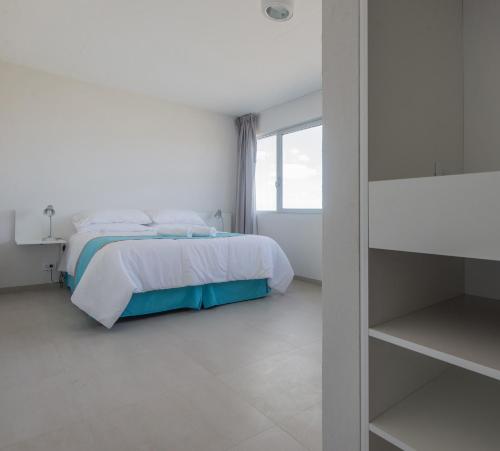 a white bedroom with a bed and a window at Vista Hotel in Villa Gesell