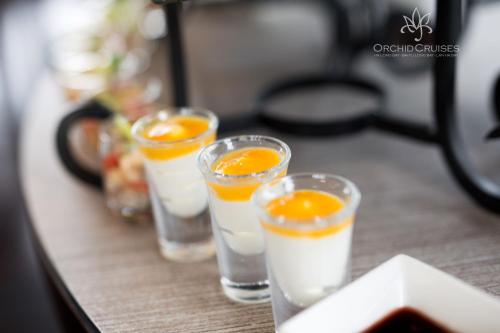 four glasses of milk and orange juice on a table at Orchid Classic Cruise in Ha Long