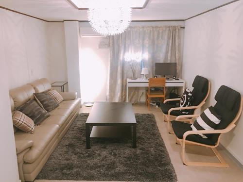 uma sala de estar com um sofá e cadeiras e uma secretária em Lux Guesthouse em Seul