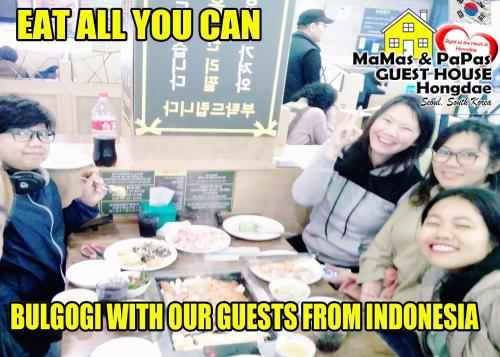 a group of people standing around a table with food at Mamas and Papas Guesthouse and Apartments in Seoul in Seoul