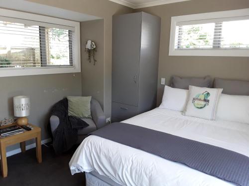 a bedroom with a white bed and a chair at Suite Petite in Taupo