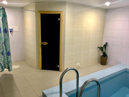 a bathroom with a tub and a black door at Teremok Guest House in Sochi
