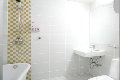 a white bathroom with a sink and a shower at Changwon Olympic Hotel in Changwon