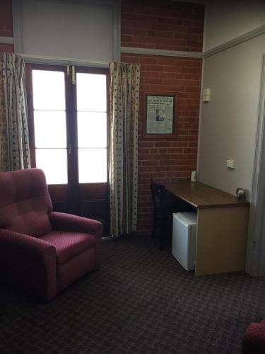 a waiting room with a desk and a chair and a table at Heritage Hotel Rockhampton in Rockhampton