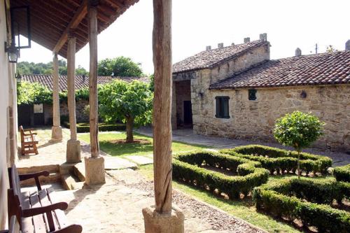 a garden with hedges and a stone building with a house at Pazo de Eidian in Eidián