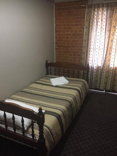 a bed sitting in a room with a window at Heritage Hotel Rockhampton in Rockhampton