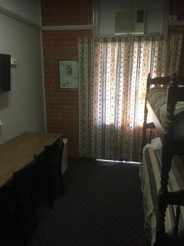 a bedroom with a bed and a window with curtains at Heritage Hotel Rockhampton in Rockhampton