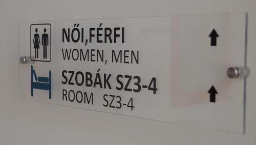 a white sign with black writing on a door at Ciszterci Szállás Pécs in Pécs