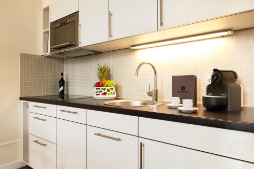 a kitchen with white cabinets and a sink at Hapimag Ferienwohnungen Dresden in Dresden