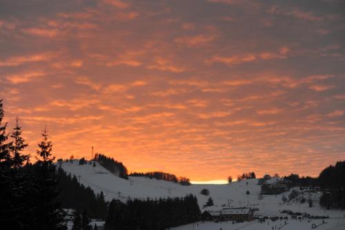 a sunset over a snow covered mountain with trees at Apartmán Tatran A 12 in Donovaly