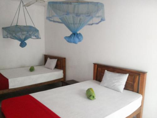 two beds in a room with blue decorations on the wall at Jayaru Guest House in Polonnaruwa
