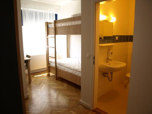 a bathroom with a sink and a bunk bed at Ciszterci Szállás Pécs in Pécs