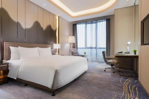 a bedroom with a large white bed and a desk at Wanda Realm Changzhou in Changzhou