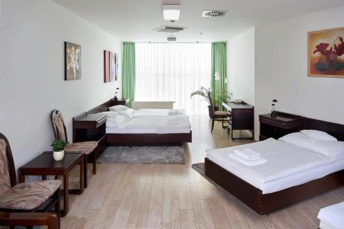 a bedroom with two beds and a table and chairs at Hotel Ankora in Prague