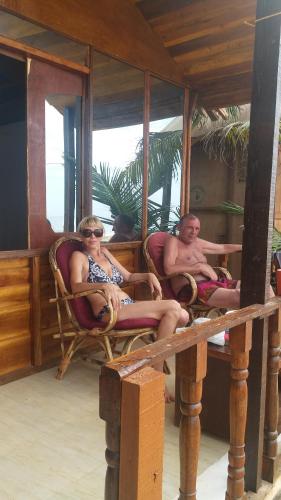 a man and a woman sitting in chairs on a porch at Madhu Huts Agonda in Agonda