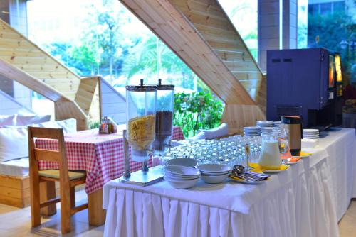 een witte tafel met borden en een vaas erop bij Te Stela Resort & SPA in Tirana