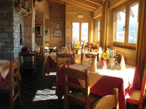 a restaurant with tables and chairs in a room at Hotel Maisonnette in Torgnon