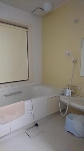 a bathroom with a bath tub and a window at Weekly Mansion Ise No.6 in Ise